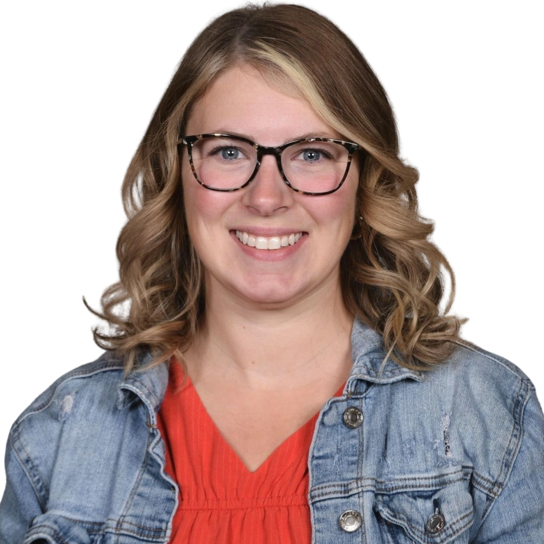Smiling blonde woman wearing a jean jacket, red shirt and glasses.